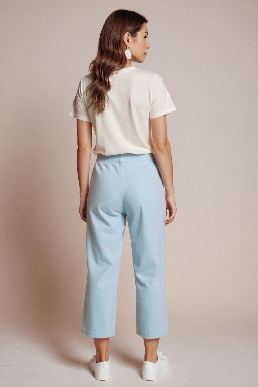 Woman wearing a white shirt and light blue pants on a beige background