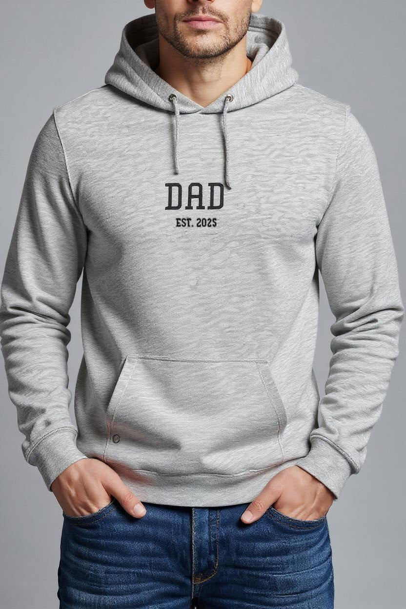 Gray hoodie with 'DAD EST. 2023' text worn by a person on a gray background