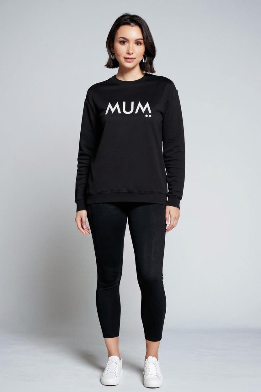 Woman wearing a black sweatshirt with 'MUM' text on a plain background