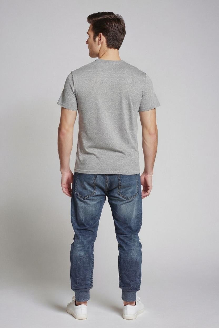 Man wearing a gray t-shirt and blue jeans on a plain background