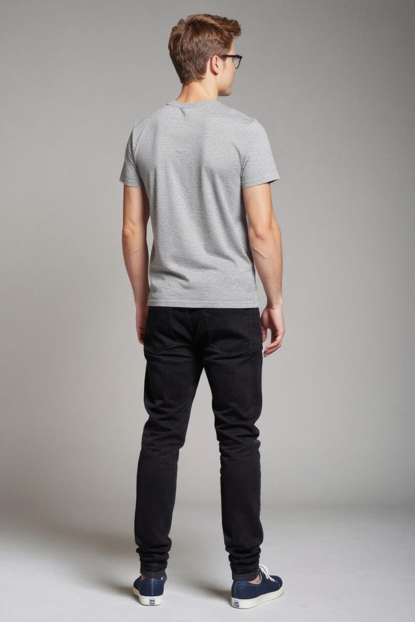 Man wearing a gray t-shirt and black pants against a plain background