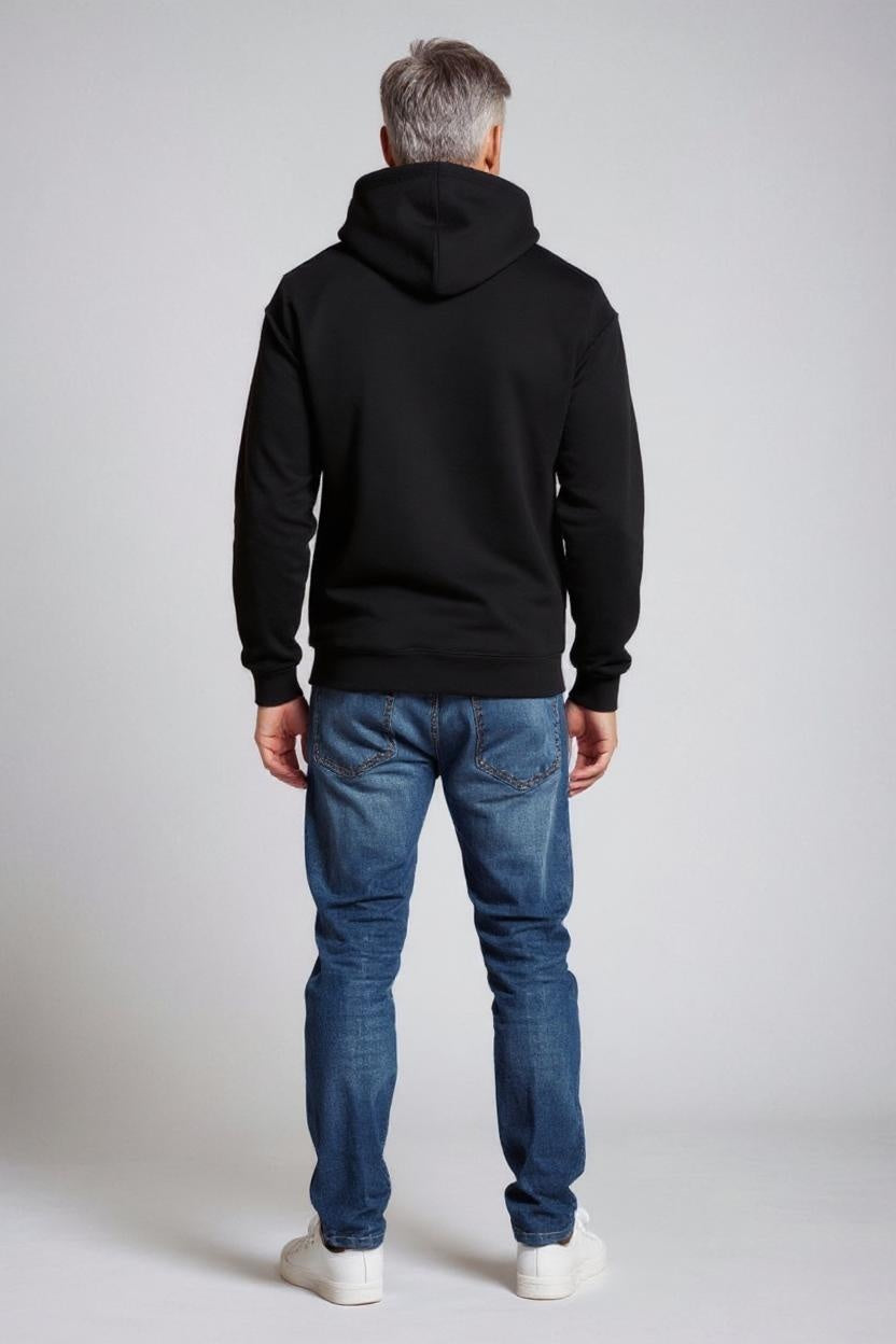 Person wearing a black hoodie and blue jeans on a plain background
