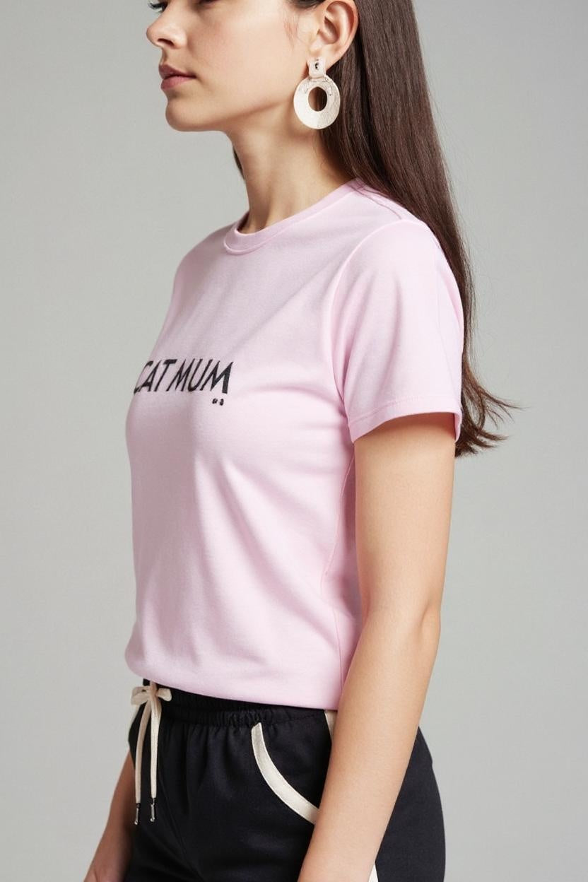 Person wearing a pink t-shirt with text and black pants on a plain background