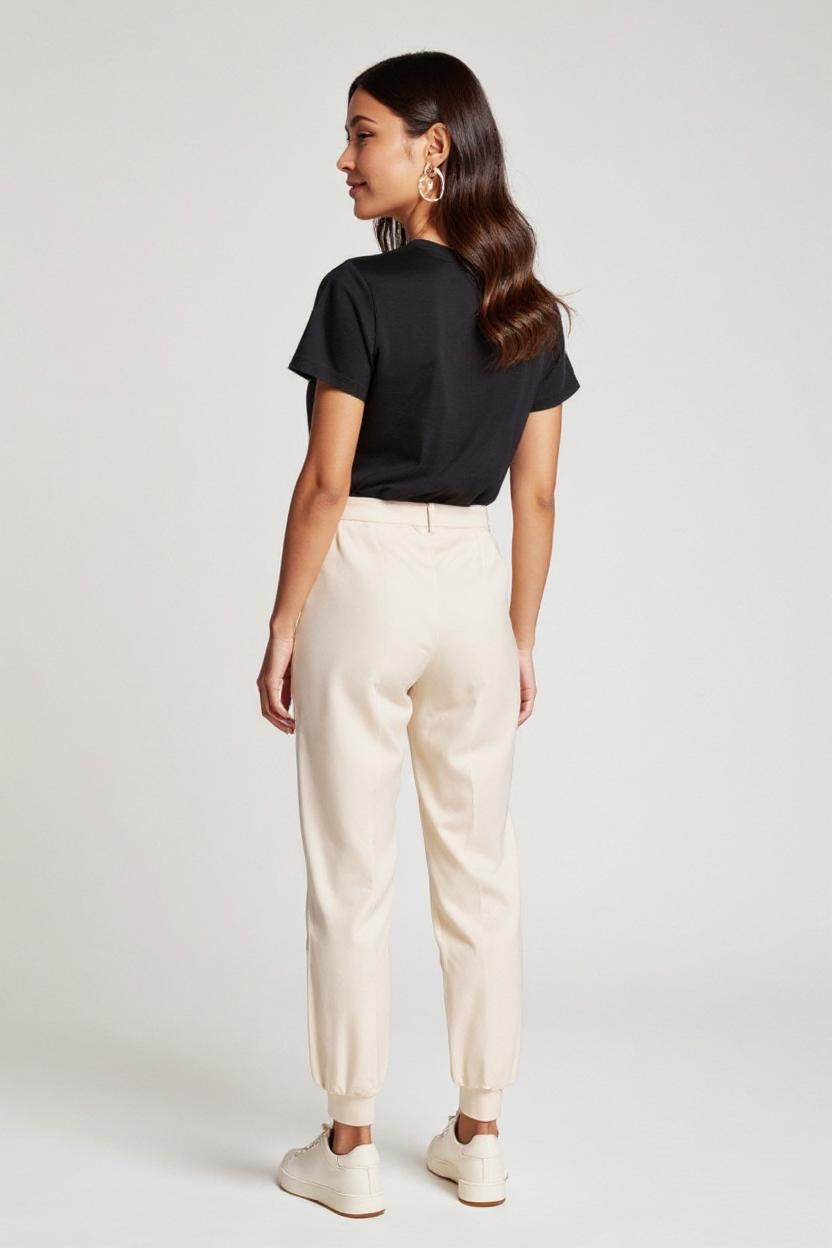 Woman wearing a black t-shirt and beige pants on a white background