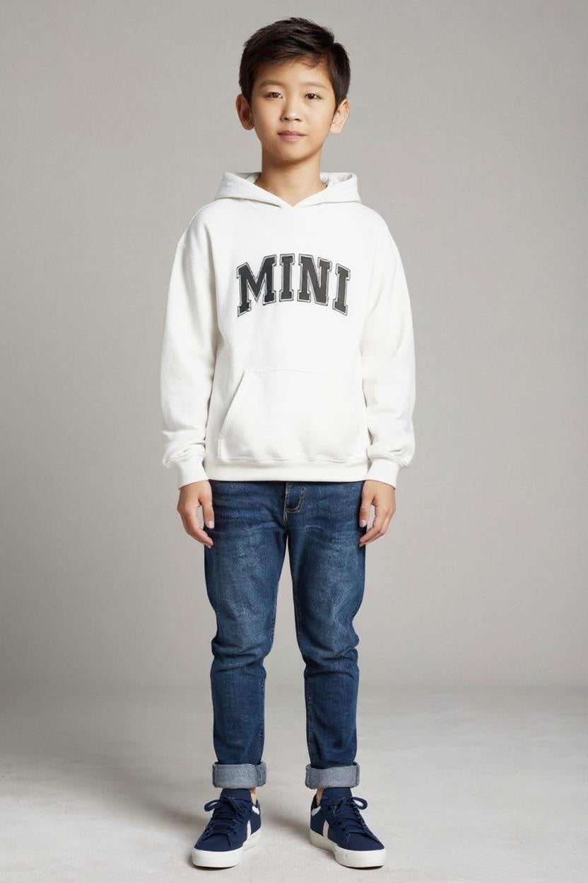 Child wearing a white hoodie with 'MINI' text and blue jeans on a plain background