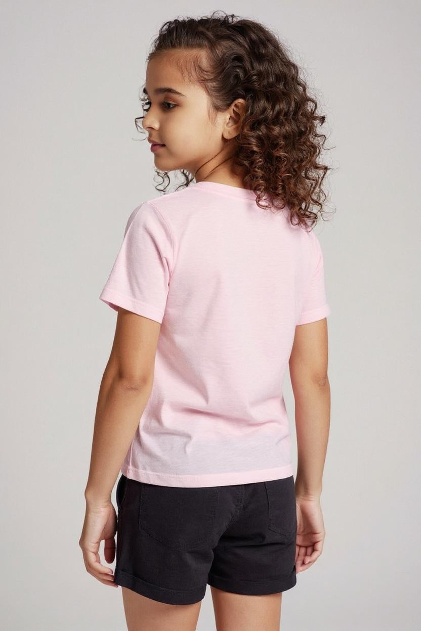Child wearing a pink t-shirt and black shorts on a plain background