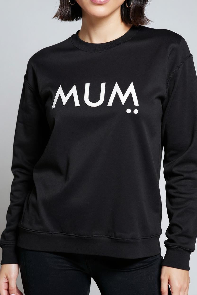 Black sweatshirt with 'MUM' printed on it worn by a person against a gray background