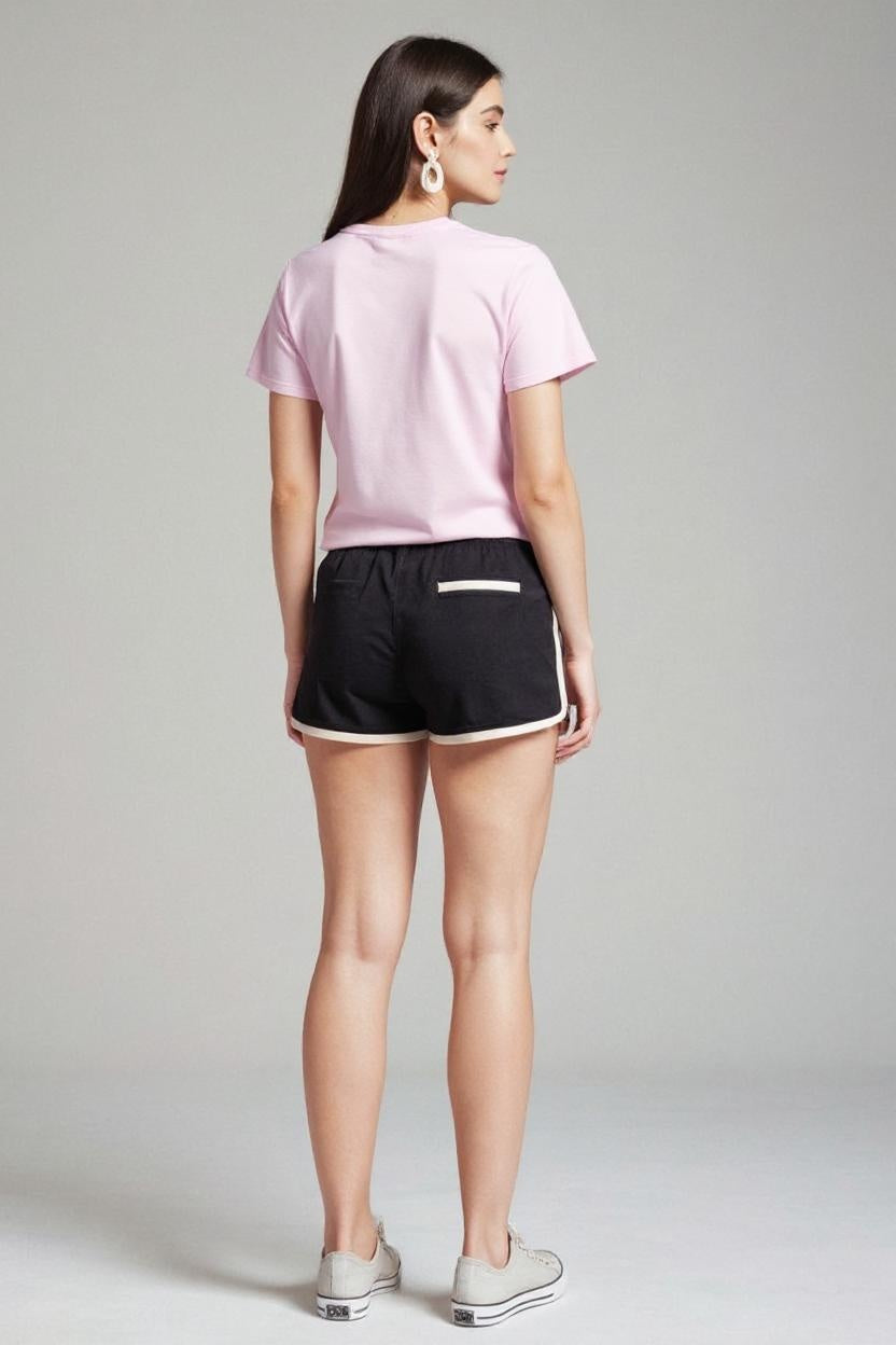 Woman wearing a pink t-shirt and black shorts on a plain background