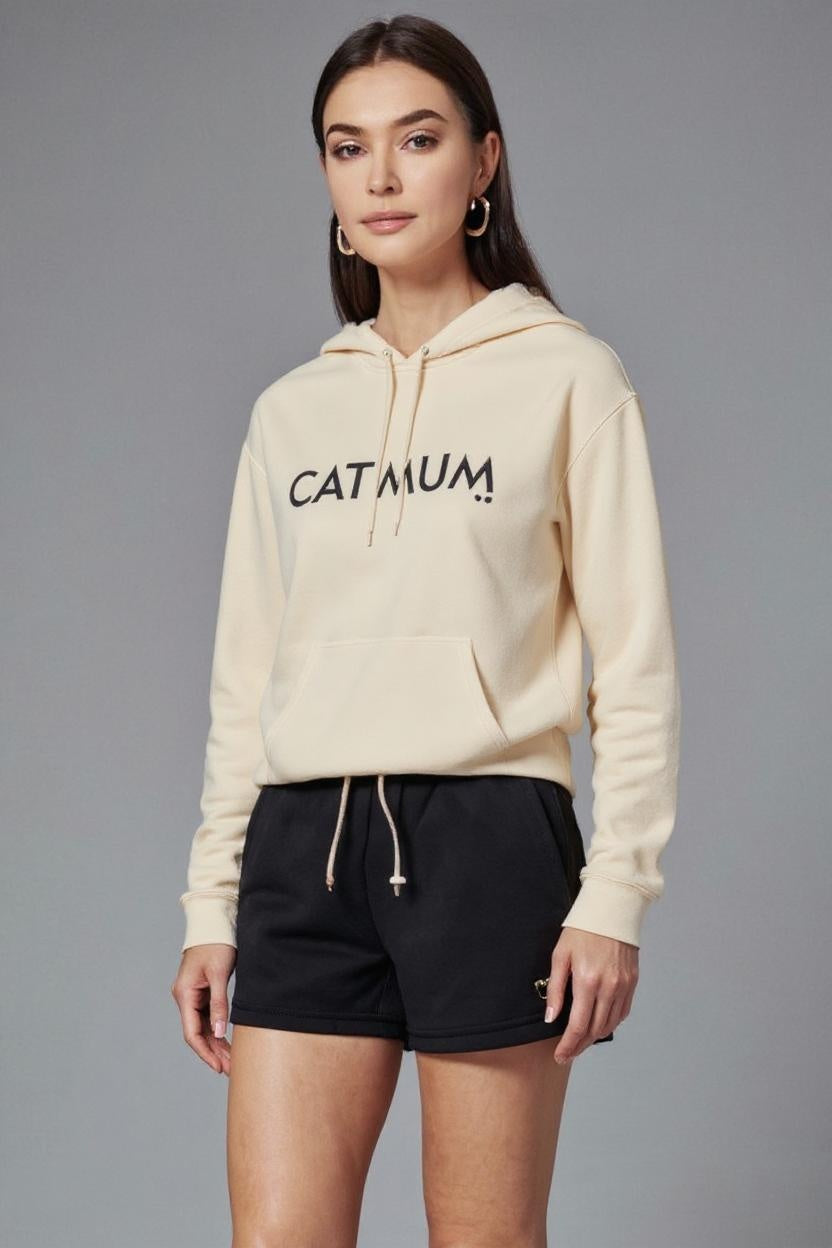 Woman wearing a cream hoodie with 'CATMUM' text and black shorts on a gray background