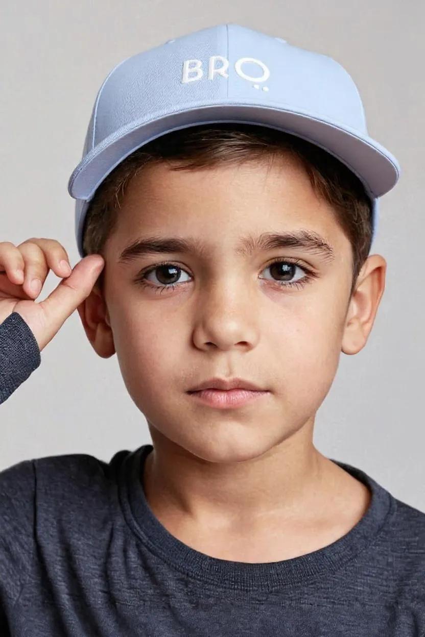 Child wearing a light blue cap with 'BRQ' logo on a plain background