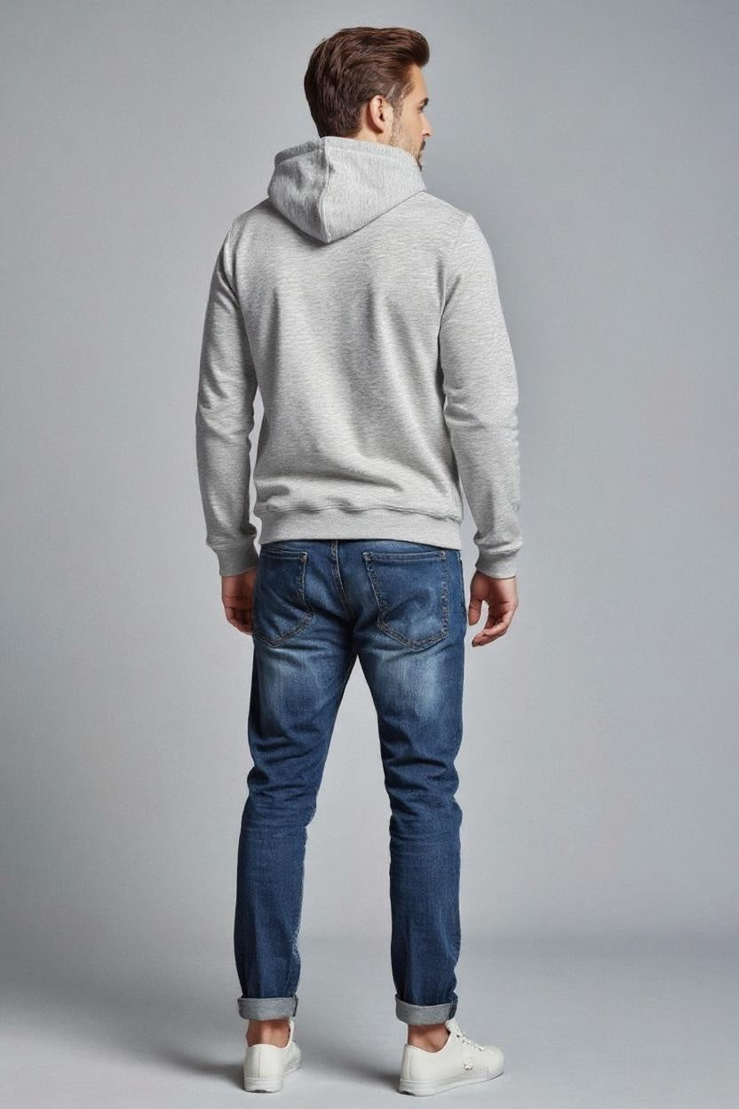 Man wearing a gray hoodie and blue jeans on a gray background