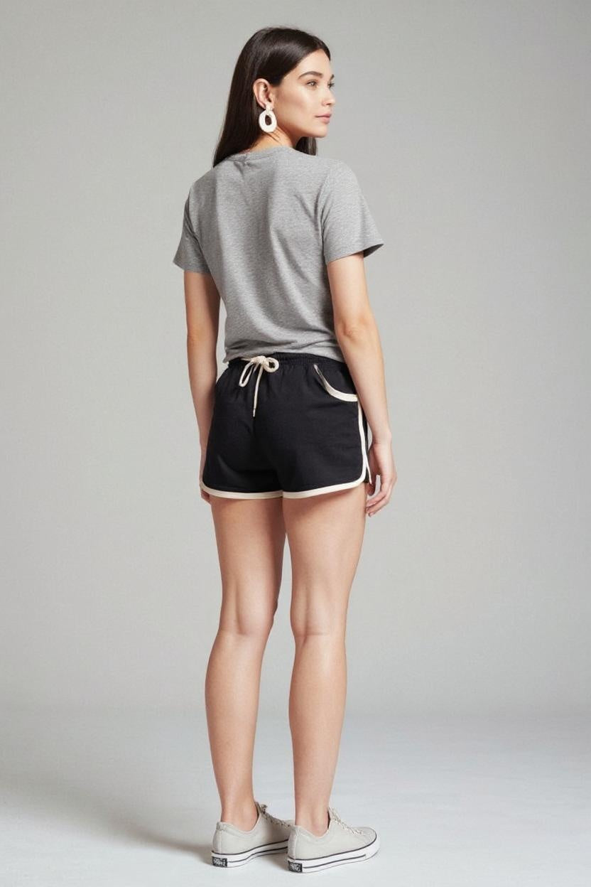 Woman wearing a gray t-shirt and black shorts on a plain background