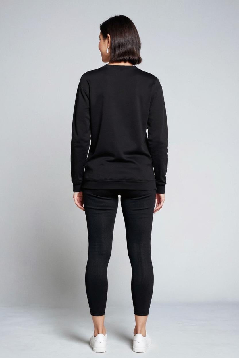 Person wearing a black long-sleeve top and black pants on a plain background