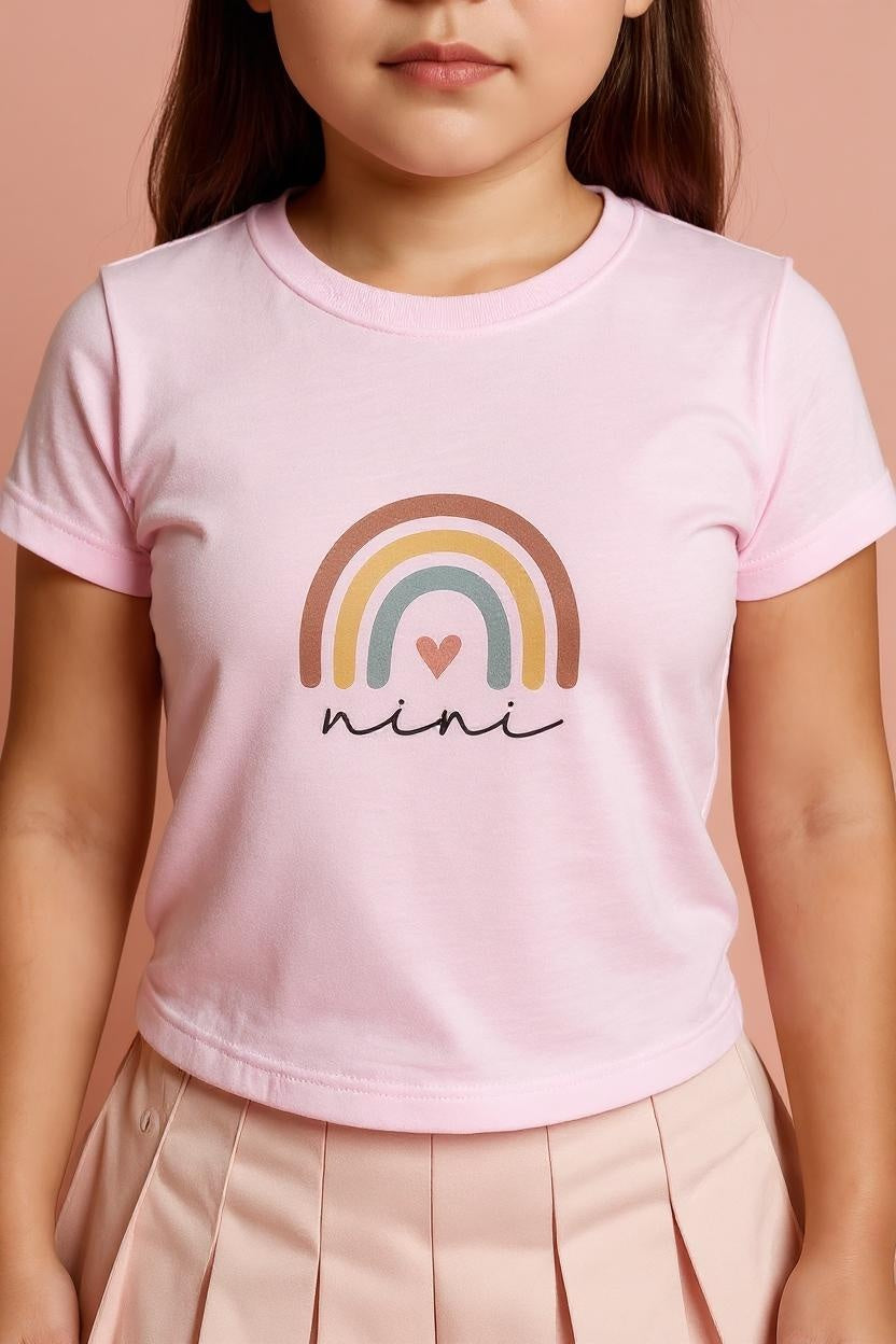 Child wearing a pink t-shirt with a rainbow and heart design, and the word 'nini'.