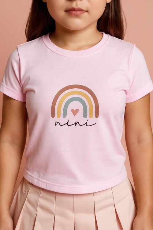 Child wearing a pink t-shirt with a rainbow and heart design, and the word 'nini'.