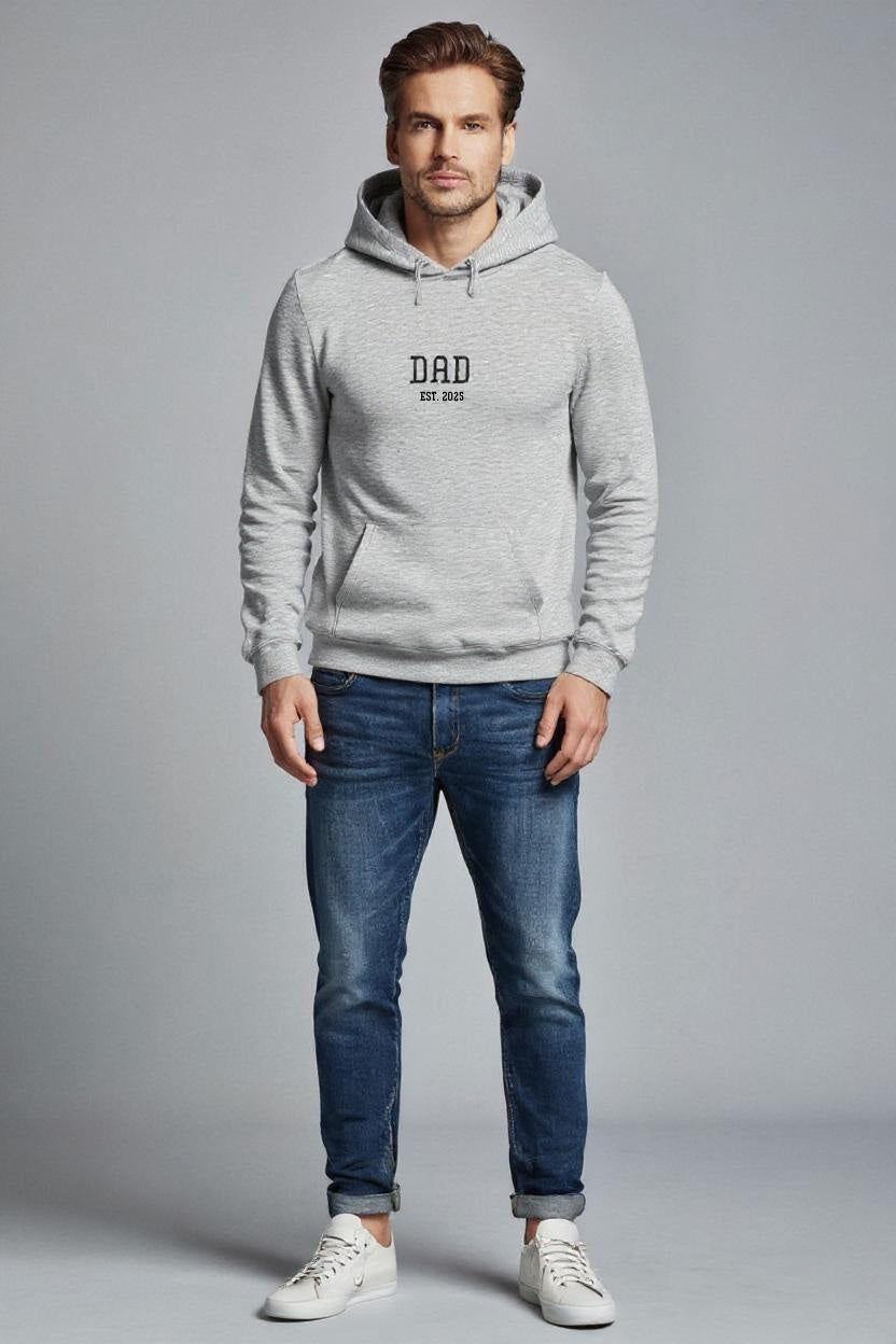 Man wearing a gray hoodie with 'DAD' printed on it, standing against a plain background