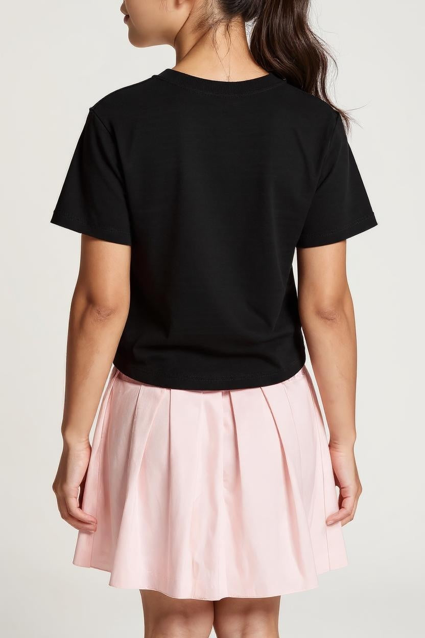 Person wearing a black t-shirt and pink skirt on a plain background