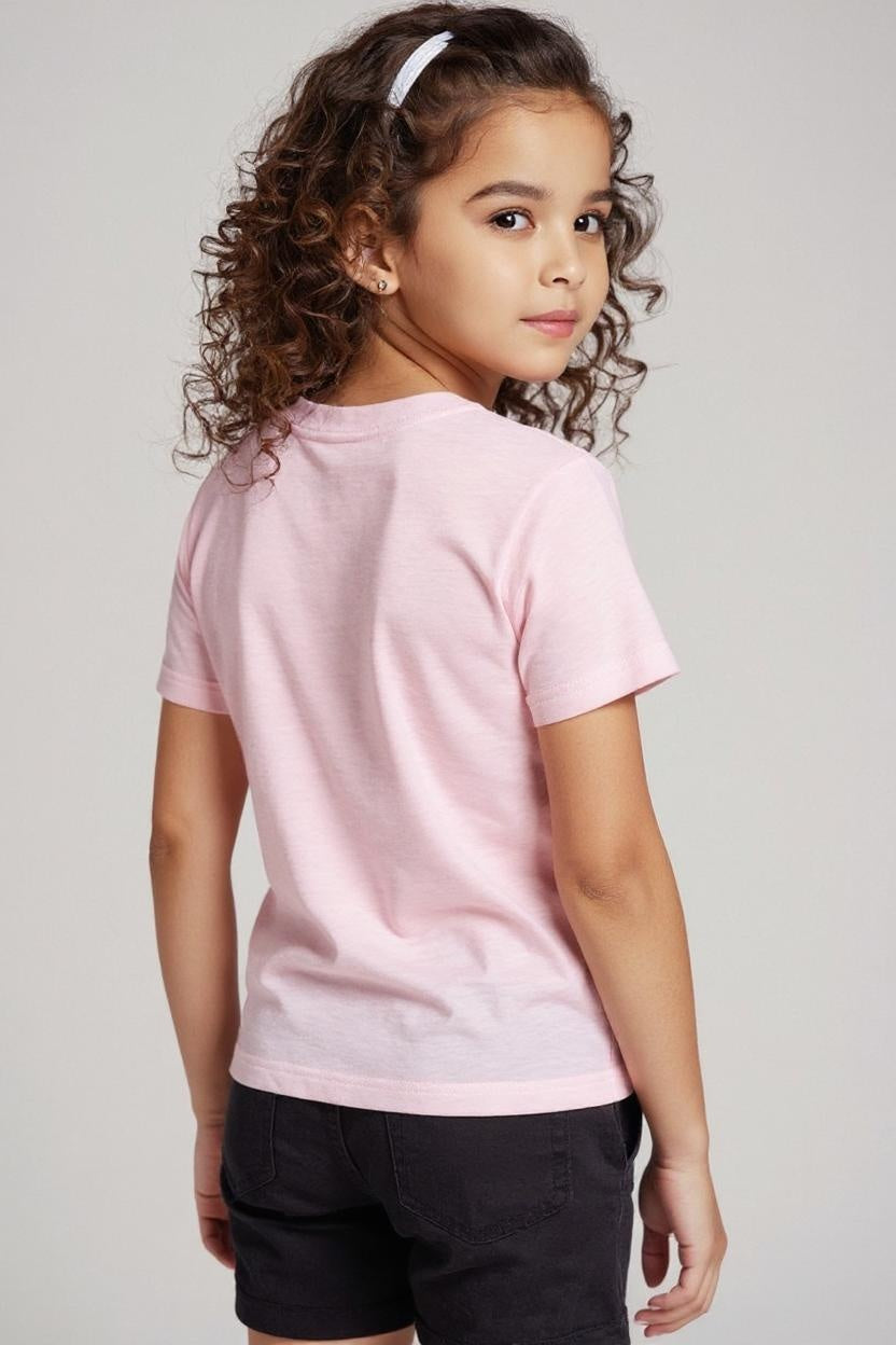 Young girl wearing a pink t-shirt and black shorts on a plain background