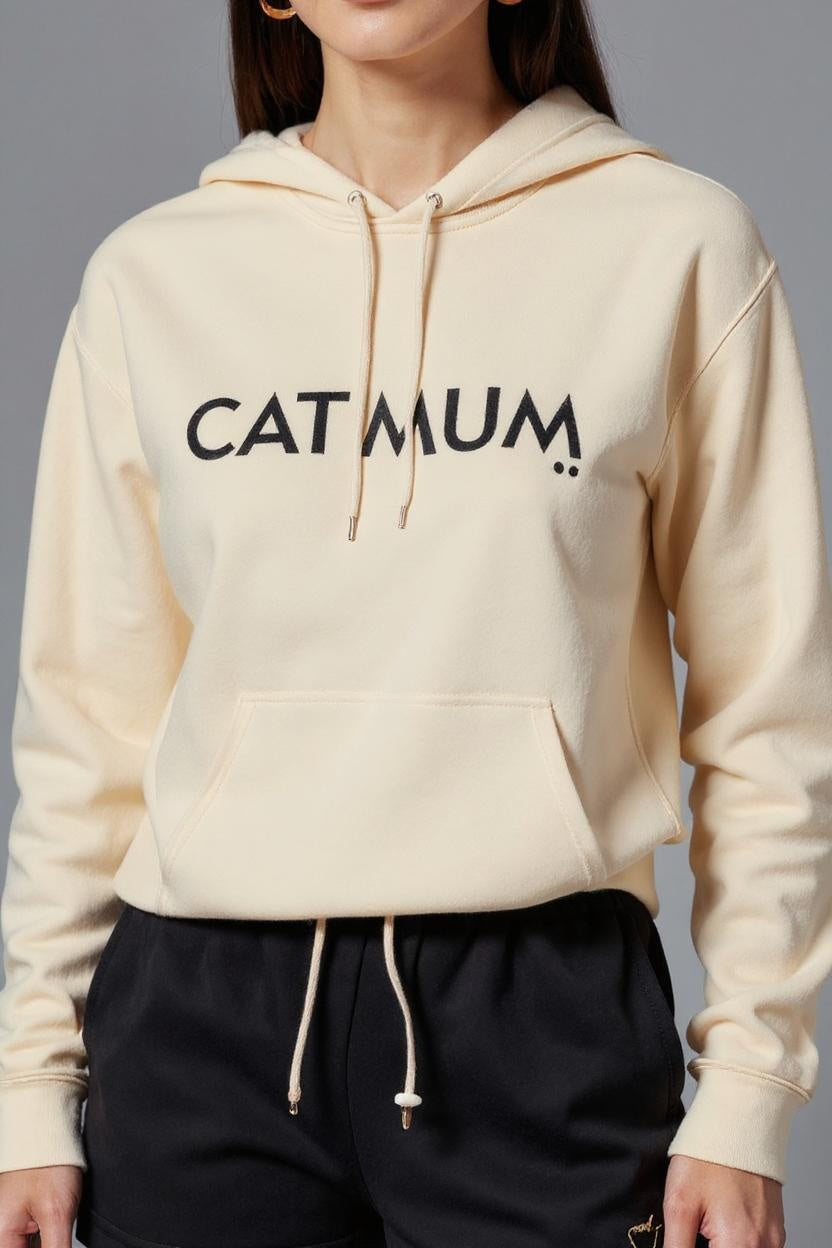Beige hoodie with 'CATMUM' text worn by a person on a gray background