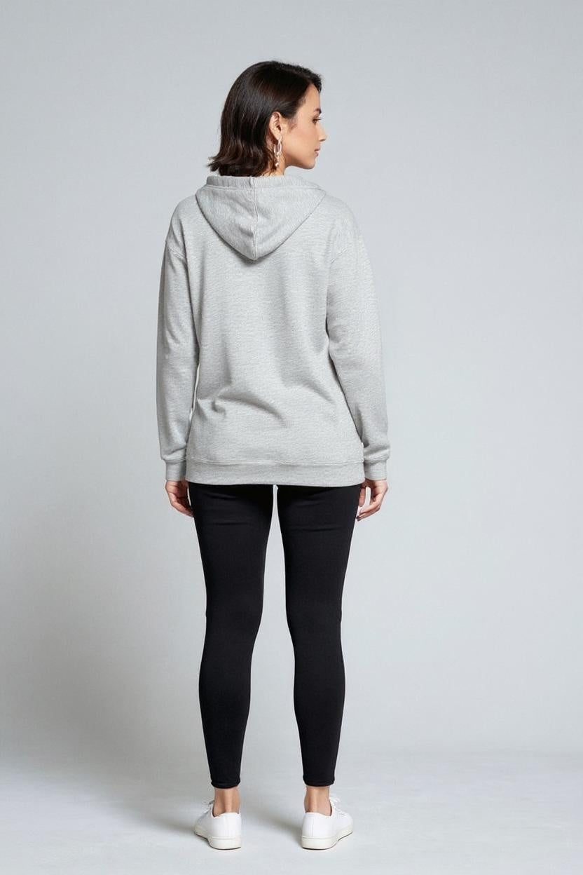 Person wearing a gray hoodie and black leggings on a light gray background