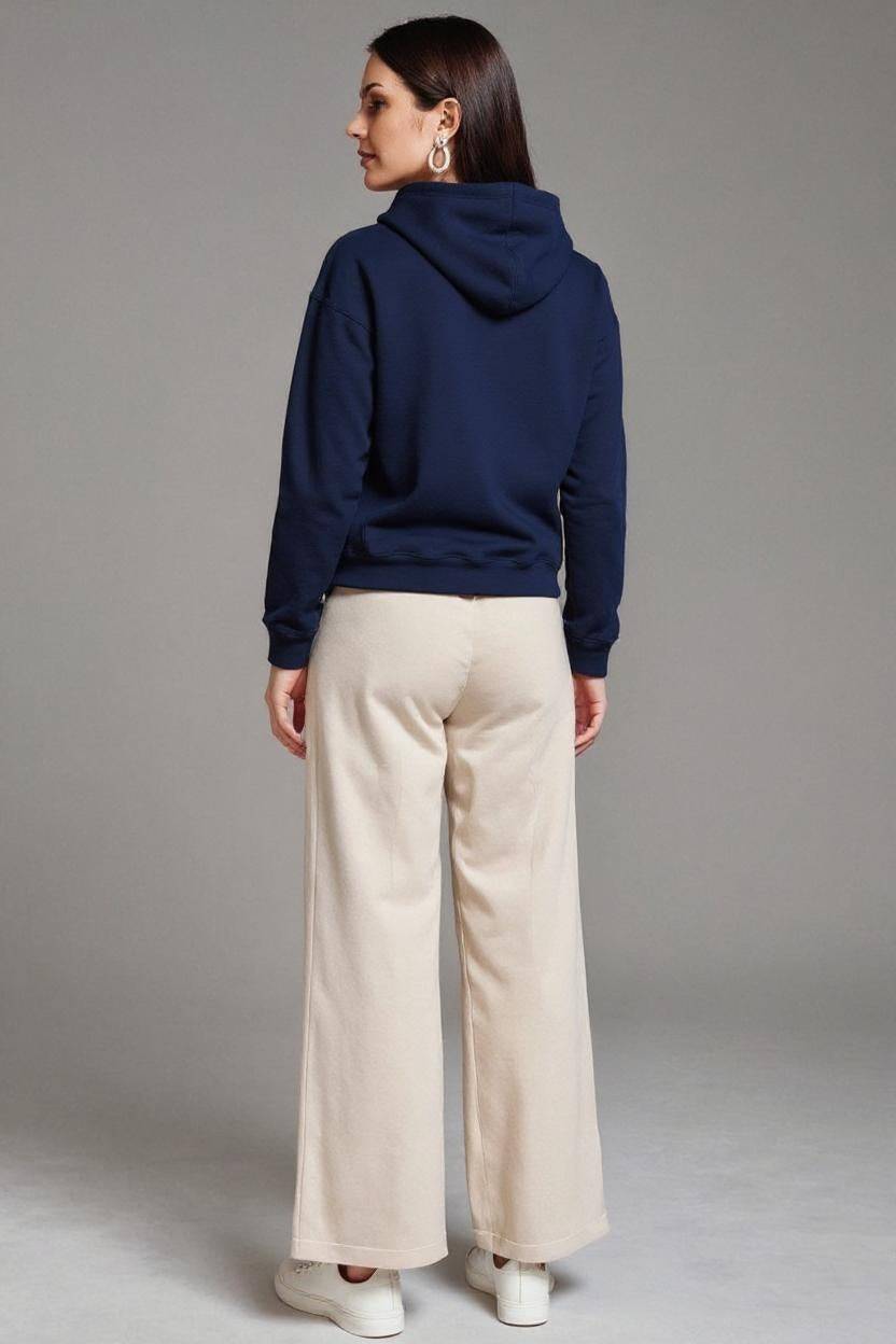 Person wearing a navy blue hoodie and beige pants on a gray background