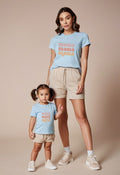 Woman and child wearing matching light blue t-shirts with 'mama' and 'minnie' text on a beige background