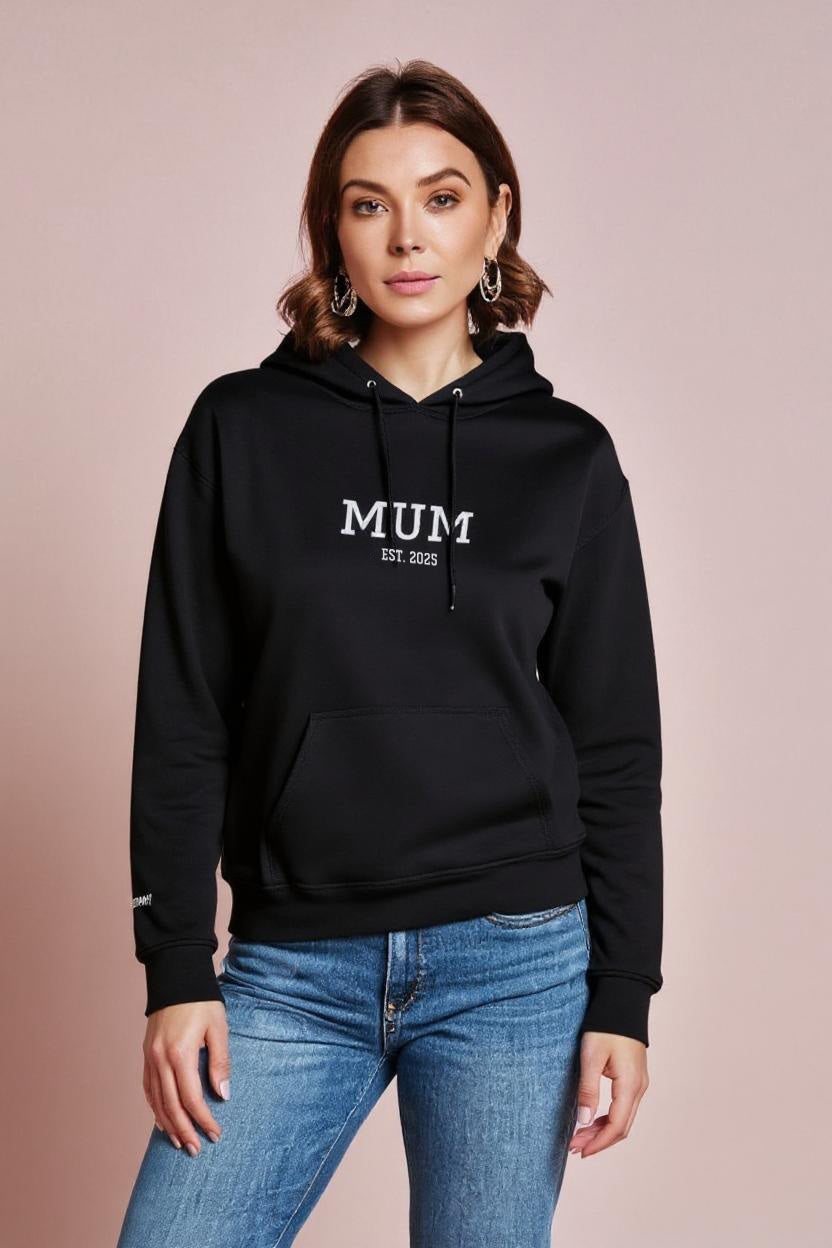 Woman wearing a black hoodie with 'MUM' text on a beige background