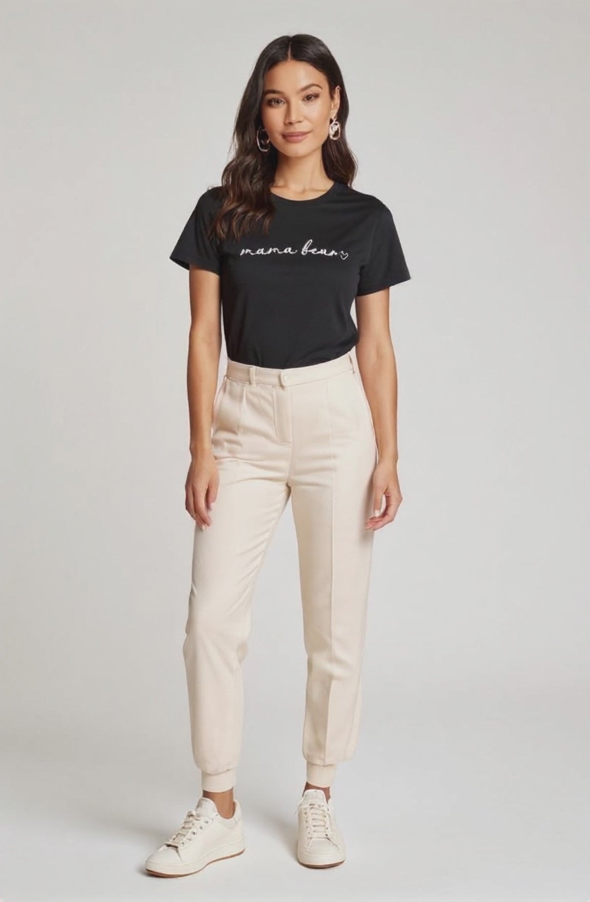Woman wearing a black 'mama bear' t-shirt and beige pants on a white background