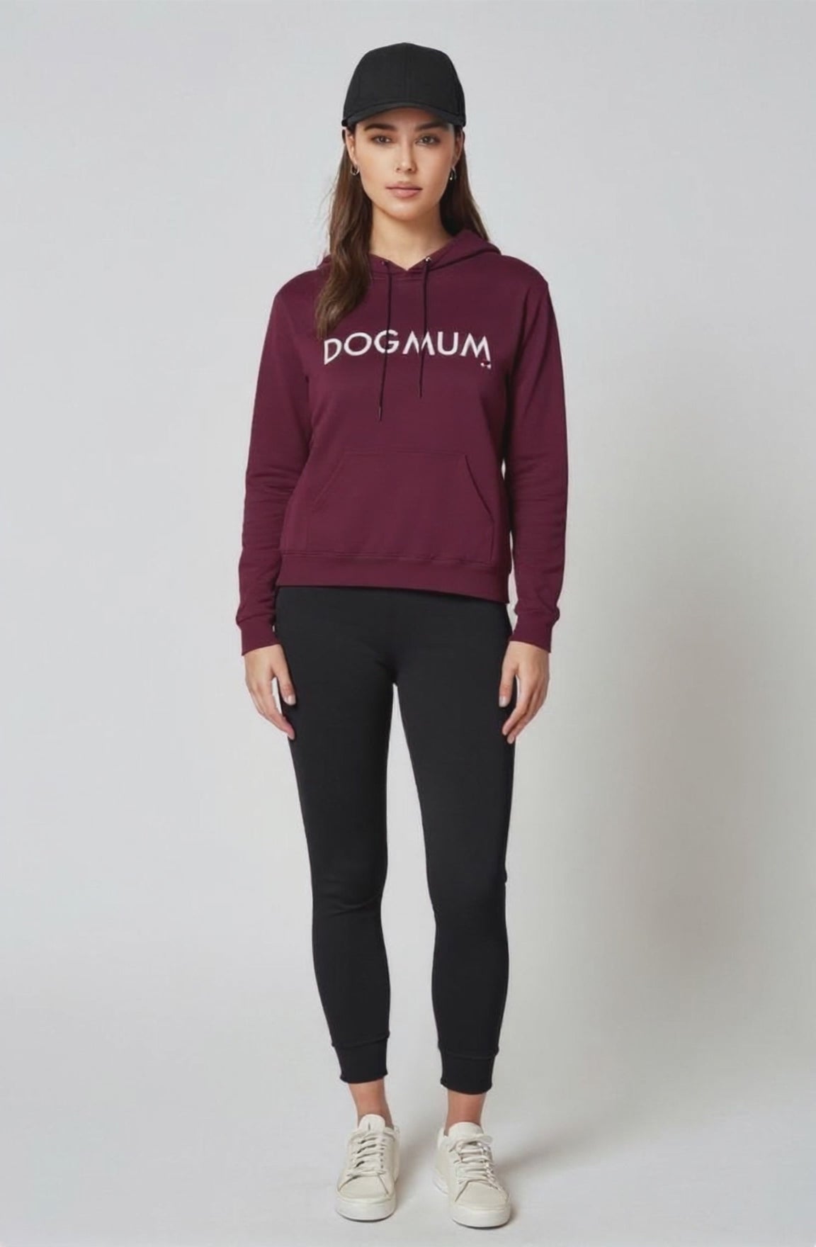 Person wearing a maroon hoodie with 'DOG mum' text, black leggings, and white sneakers on a white background