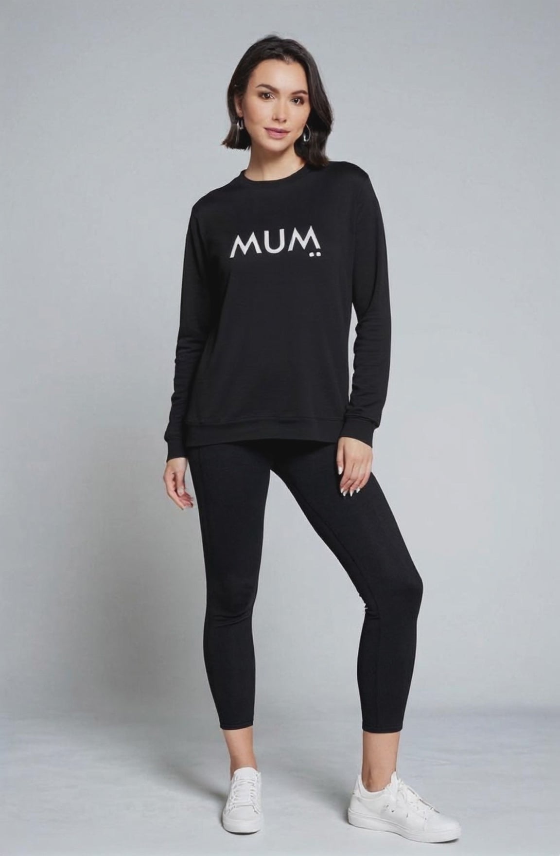 Woman wearing a black sweatshirt with 'MUM' text on a plain background